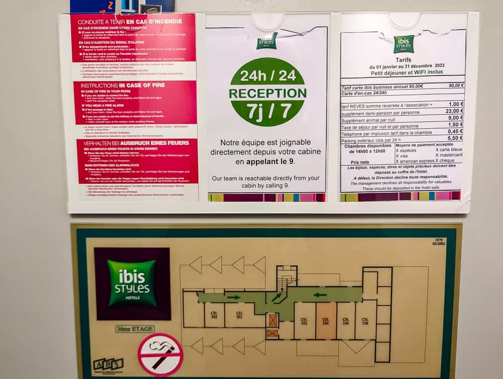 Panneau mural indiquant consignes incendie, tarifs et plan d'évacuation de l'hôtel Ibis Styles Ouistreham