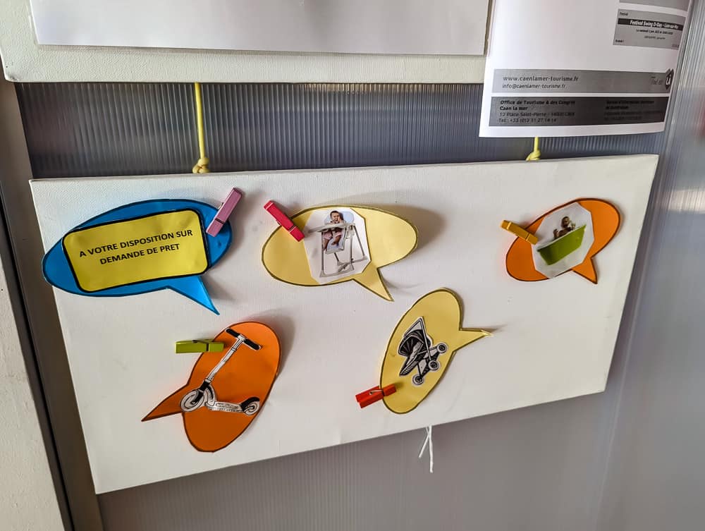 Panneau coloré avec bulles de dialogue affichant des photos d'objets prêtables à l'hôtel Ibis Styles Ouistreham