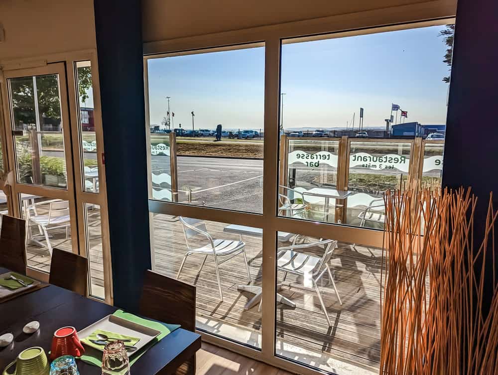 Salle du restaurant lumineuse avec vue sur la terrasse et la mer à travers de grandes baies vitrées