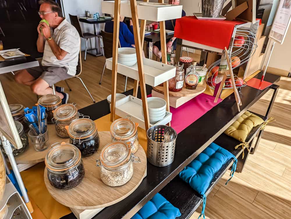 Buffet petit-déjeuner de l'hôtel Ibis Styles Ouistreham avec bocaux de céréales, confitures et fruits frais