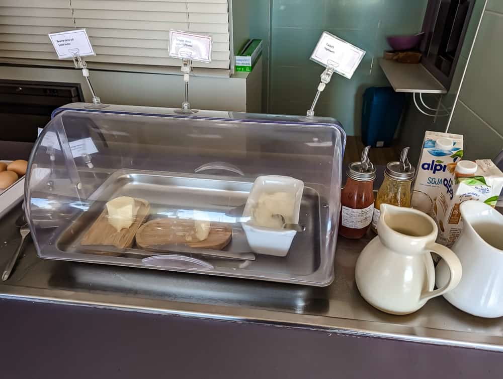 Plateau du petit-déjeuner avec beurres sous cloche, yaourt, jus végétaux et condiments à l'Ibis Styles Ouistreham