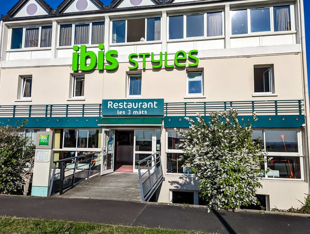 Façade claire de l'hôtel Ibis Styles Ouistreham avec entrée du restaurant Les 3 mâts et rampes d'accès