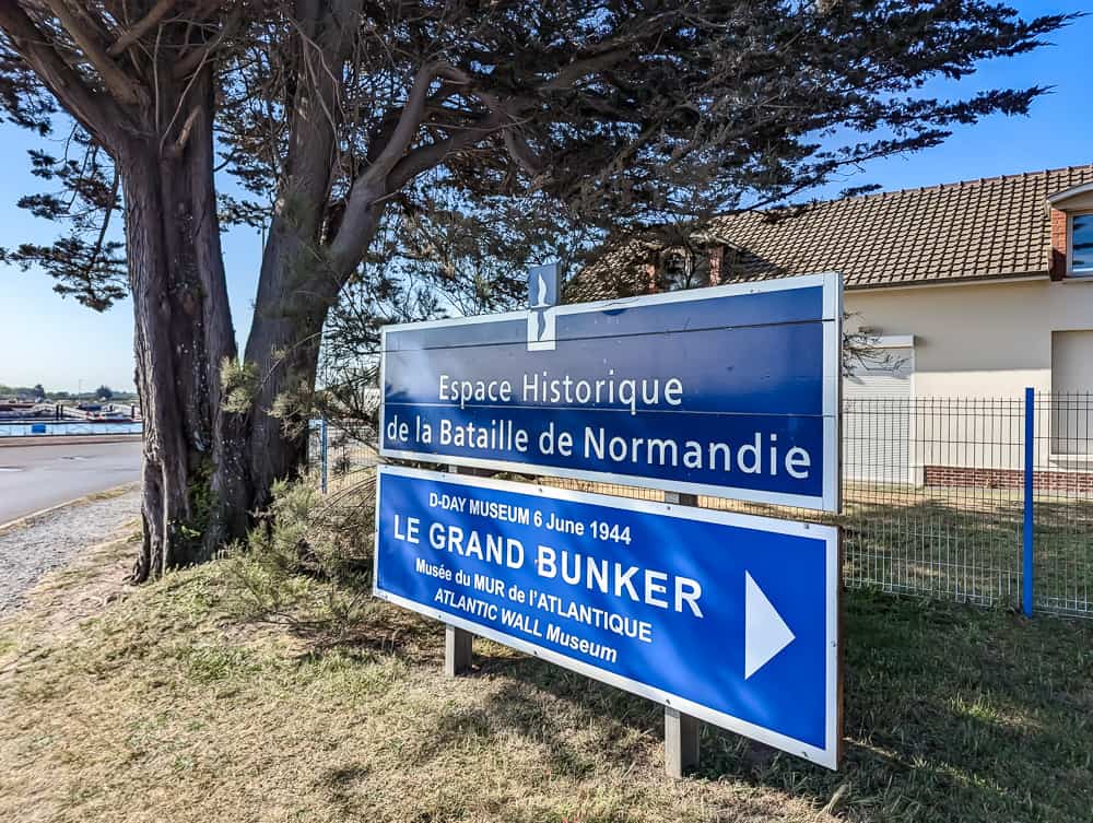 Panneau bleu indiquant l'Espace Historique de la Bataille de Normandie et le Grand Bunker à Ouistreham