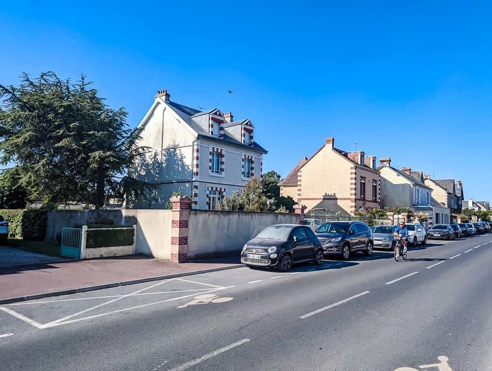 Façade blanche de l'hôtel Ibis Styles Ouistreham avec briques rouges et voitures stationnées le long de la rue