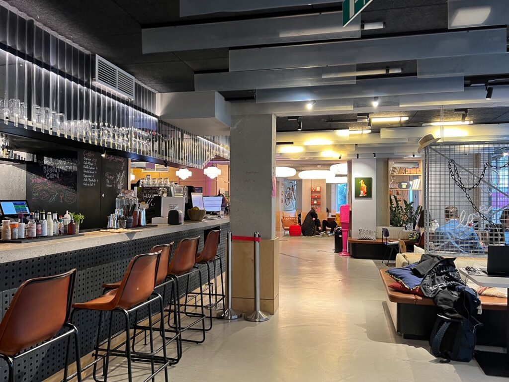 Bar moderne avec tabourets en cuir et espace salon coloré dans le lobby du Moxy Paris Bastille.