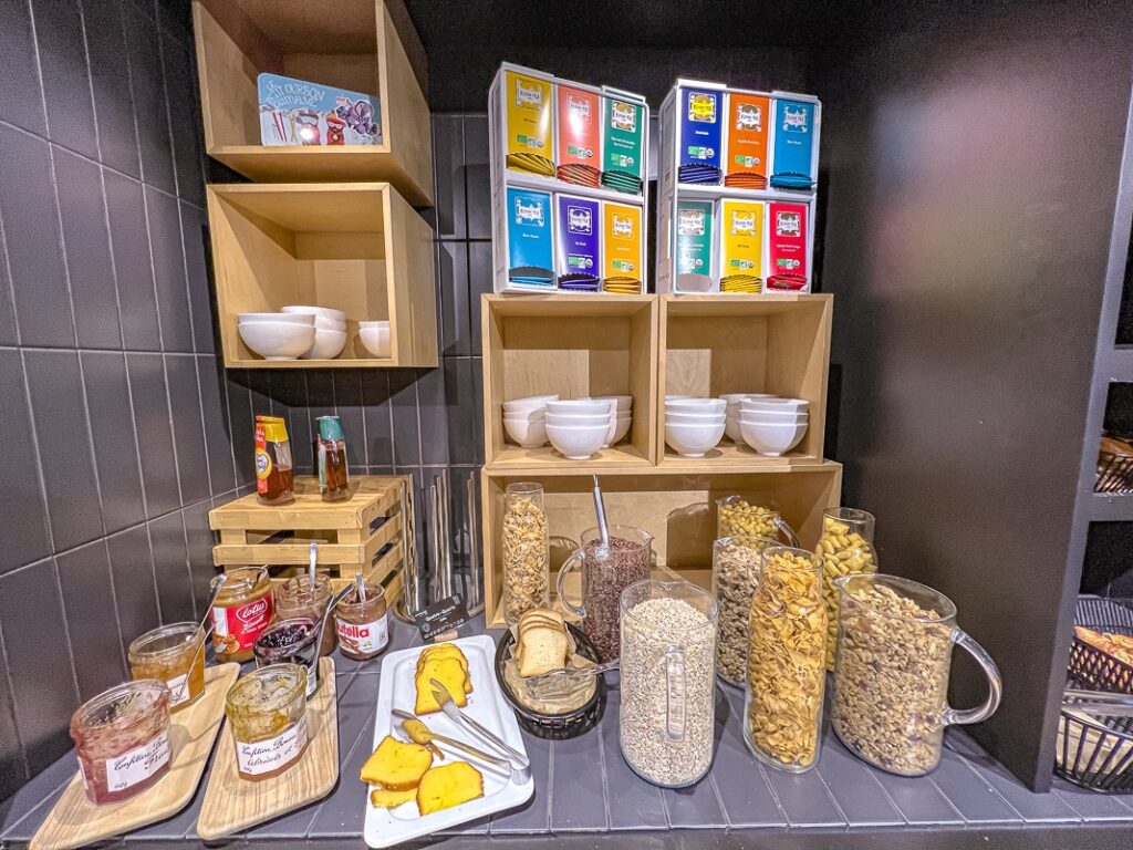 Buffet petit-déjeuner avec céréales, confitures, pains, pots de Nutella et bols blancs au Moxy Paris Bastille.