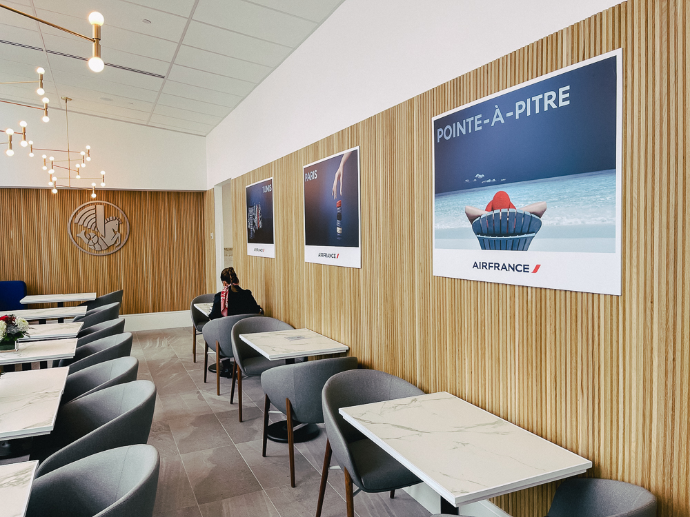 Espace de restauration moderne au salon Air France Montréal avec affiches destinations et mobilier design.