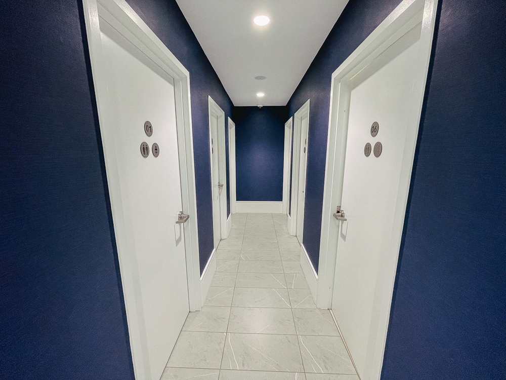 Couloir aux murs bleus menant à plusieurs cabines de douches au salon Air France Montréal.