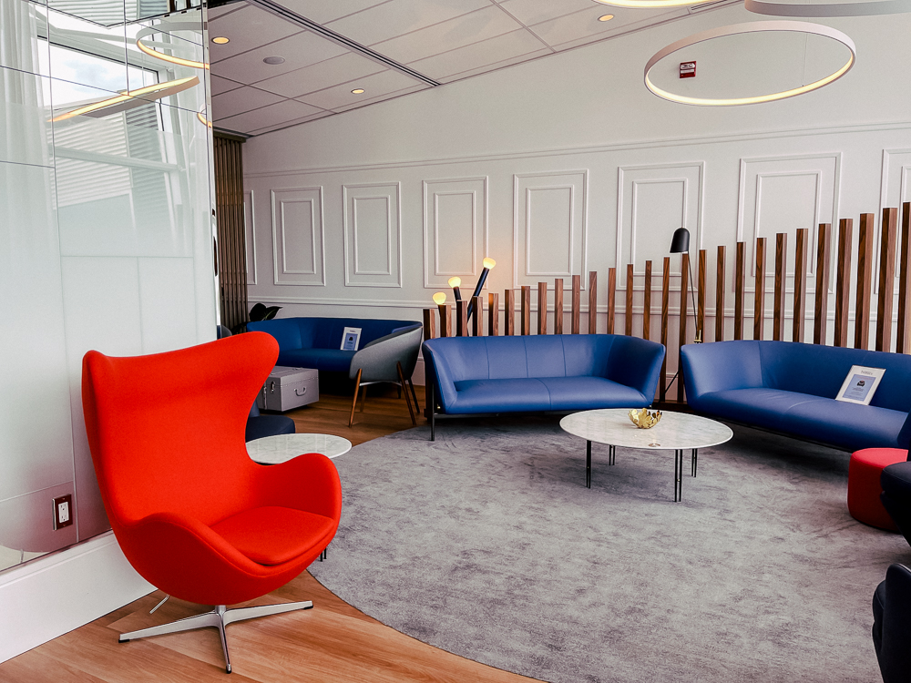Espace détente du salon Air France à Montréal avec fauteuil rouge et canapés bleus modernes.