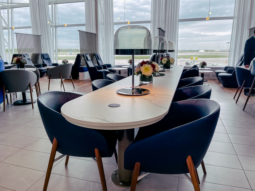 Salle lumineuse du salon Air France à Montréal avec sièges bleus et vue sur les pistes.