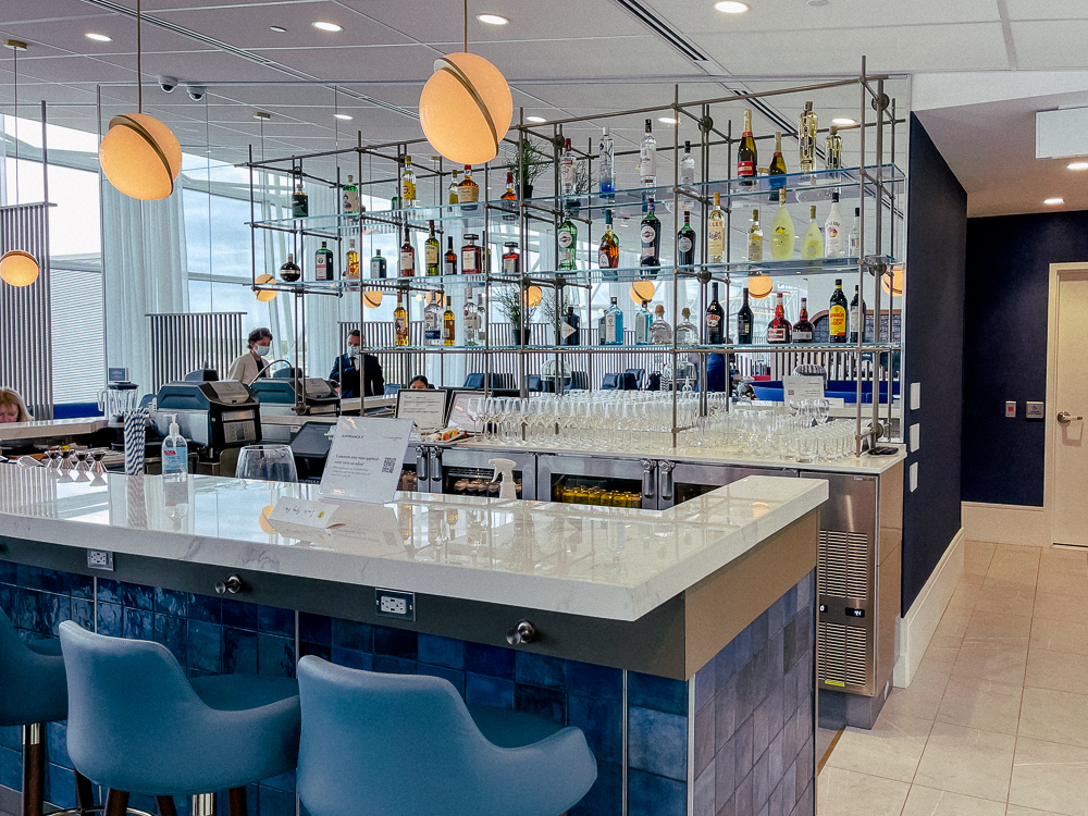 Bar moderne du salon Air France à l'aéroport de Montréal avec bouteilles et verres alignés.