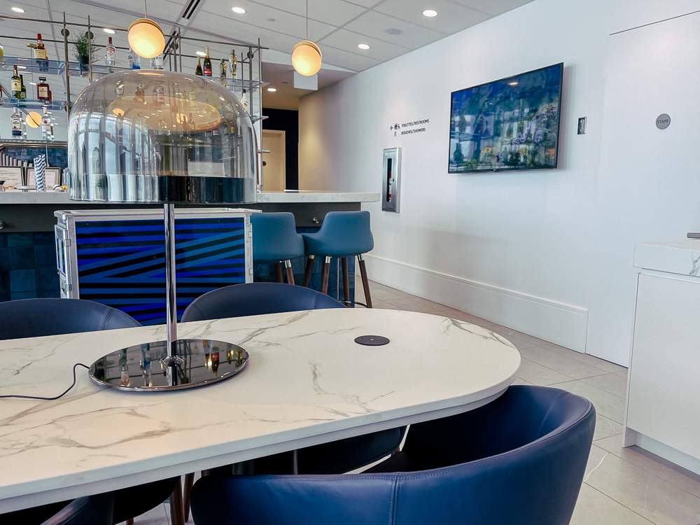Espace moderne du salon Air France à Montréal avec bar, chaises bleues et éclairage design.