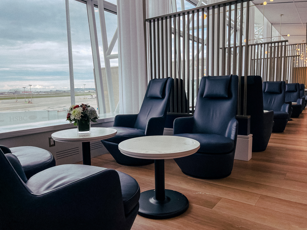 Fauteuils bleus confortables au salon Air France de Montréal avec vue sur les pistes de l'aéroport.