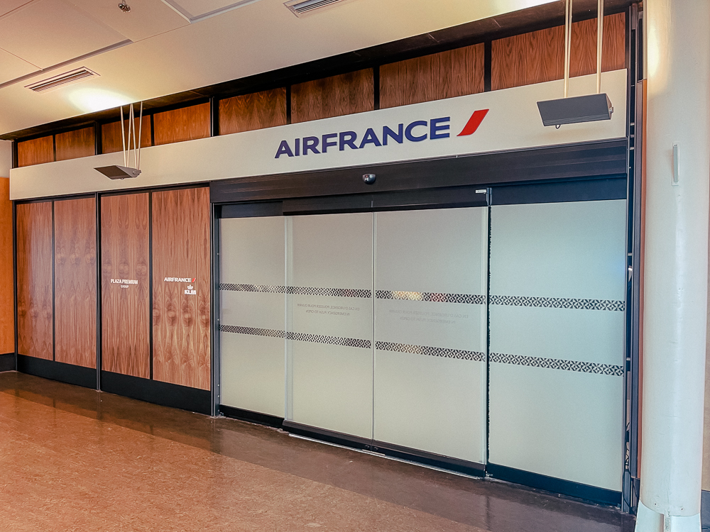 Entrée du salon Air France à l'aéroport de Montréal avec portes vitrées et logo visible.