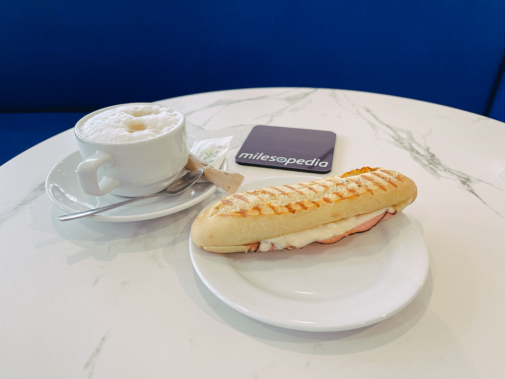 Cappuccino et panini servis sur table blanche au salon Air France de l'aéroport Montréal-Trudeau.