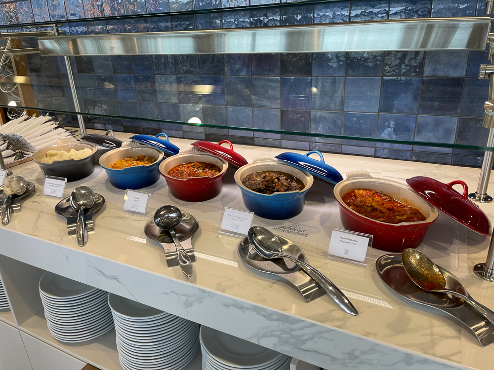 Buffet chaud au salon Air France de Montréal avec plusieurs plats servis dans des cocottes colorées.