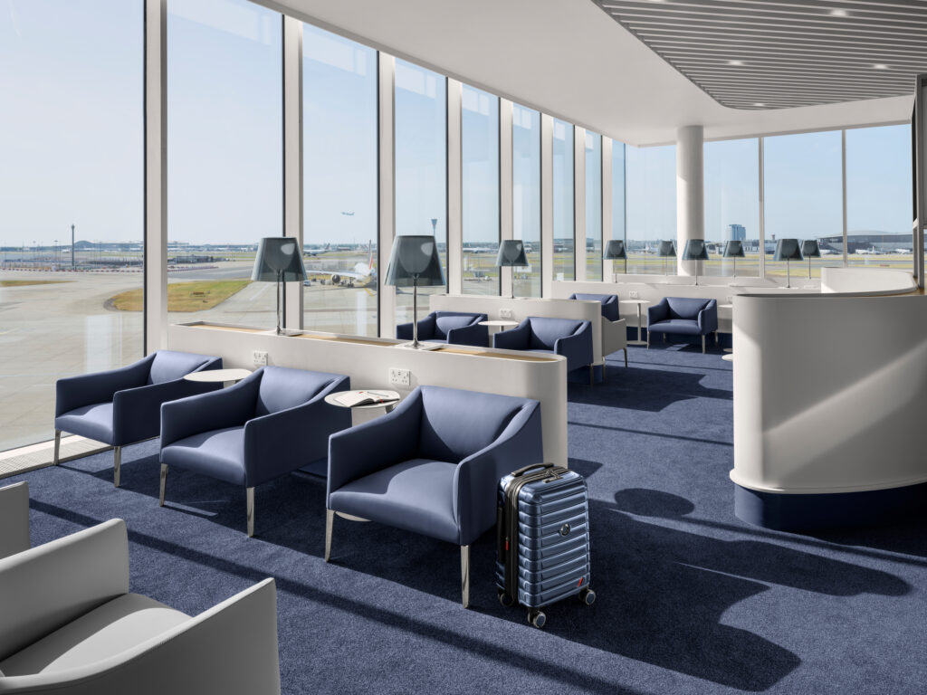 Salon Air France lumineux à Heathrow avec fauteuils bleus, grandes baies vitrées et vue sur les pistes