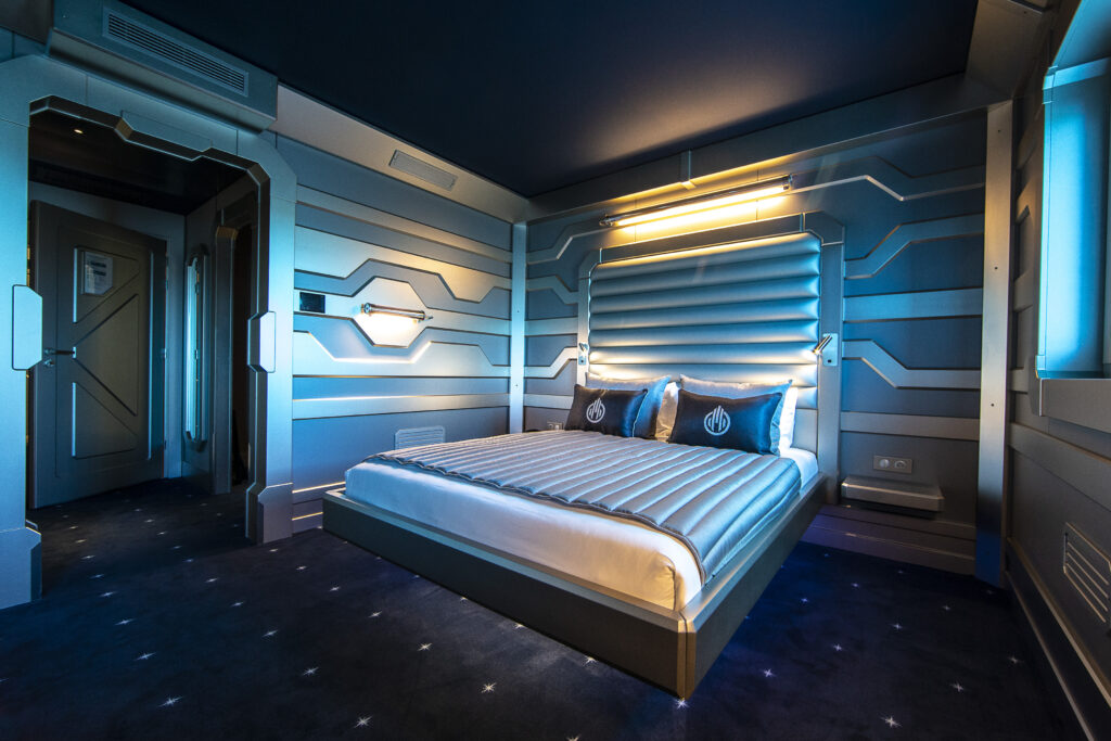 Chambre futuriste bleutée de l'Hôtel Station Cosmos au Futuroscope avec lit double éclairé