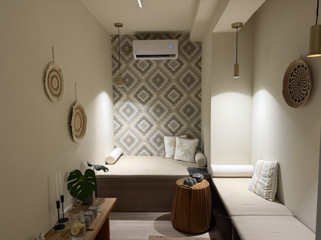 Coin détente intérieur aux tons beiges avec banquettes, coussins et décor bohème au Numo Ierapetra.