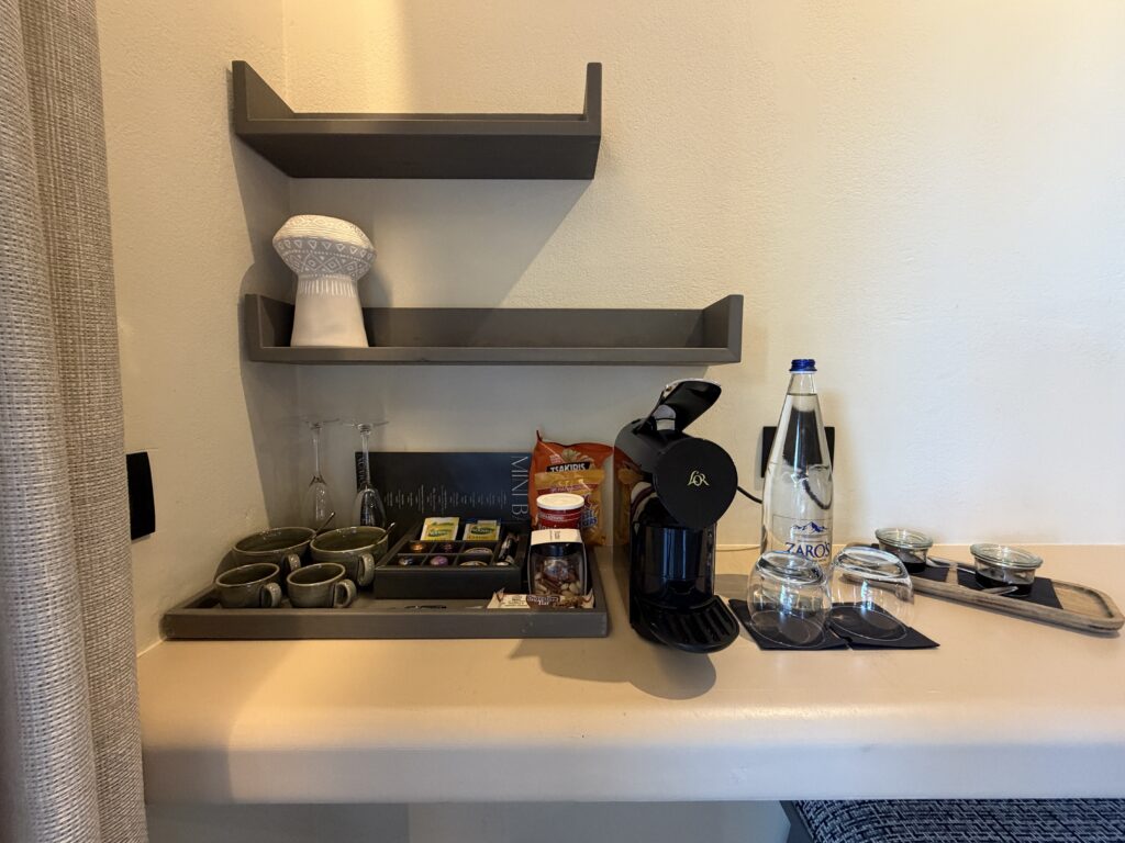 Plateau de courtoisie avec machine à café noire, tasses vertes, snacks et bouteille d’eau Zaros.