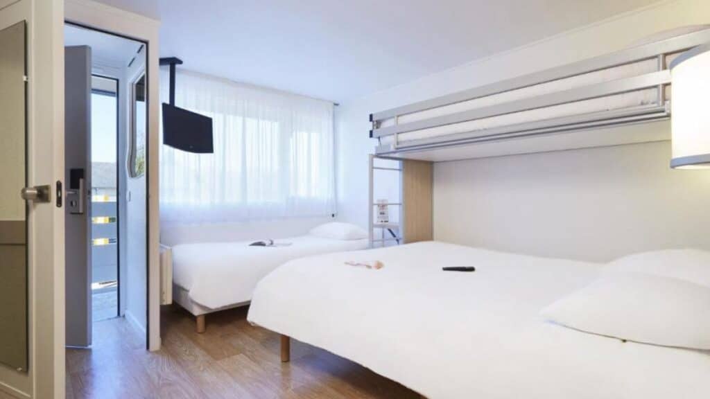 Chambre lumineuse de l'hôtel Première Classe Poitiers Futuroscope avec deux lits et un lit superposé.