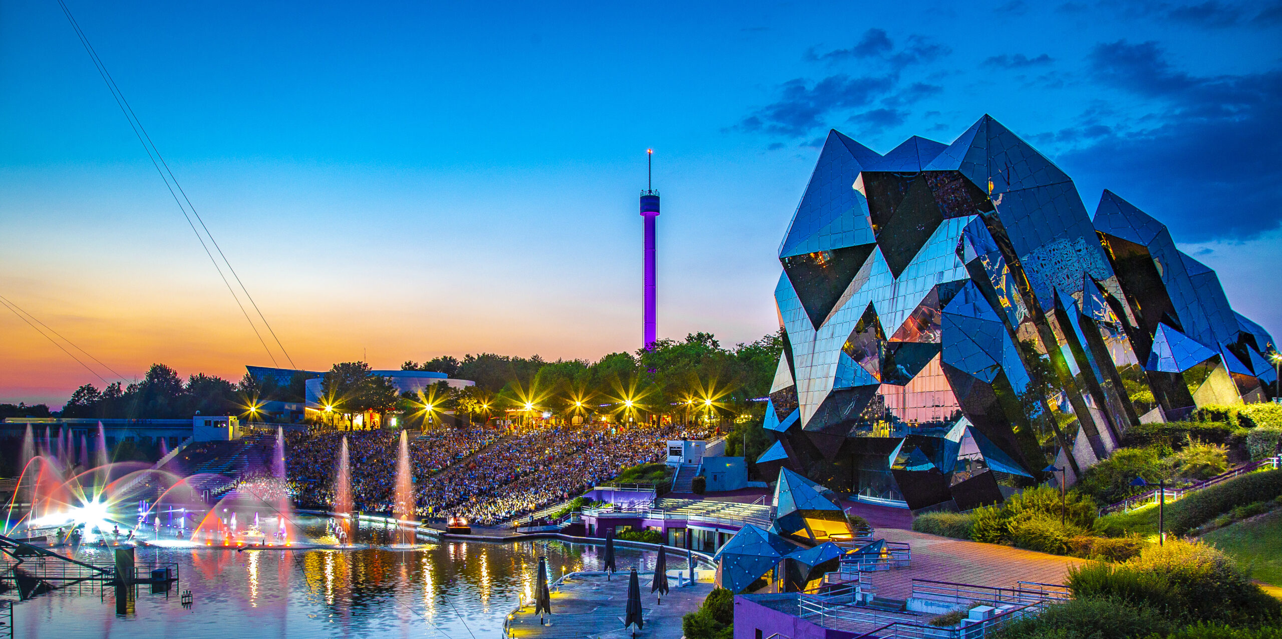 Spectacle nocturne du Futuroscope avec jets d'eau colorés devant le bâtiment futuriste illuminé
