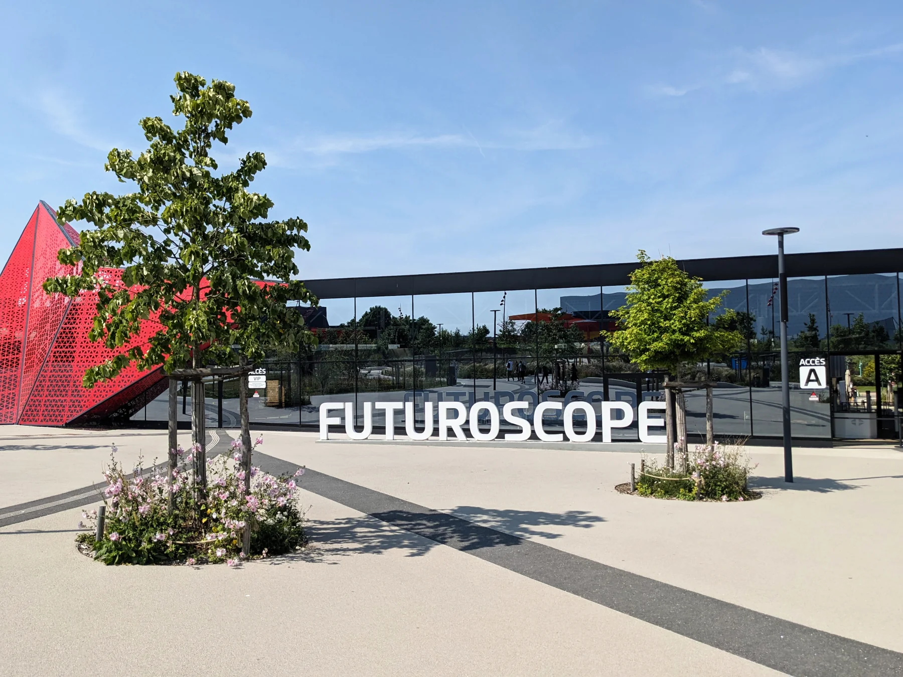 Entrée moderne du parc Futuroscope avec façade vitrée et structure rouge géométrique