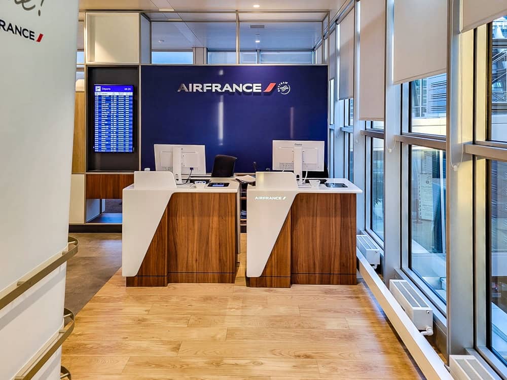 Comptoirs d'accueil en bois du salon devant un mur bleu au logo Air France
