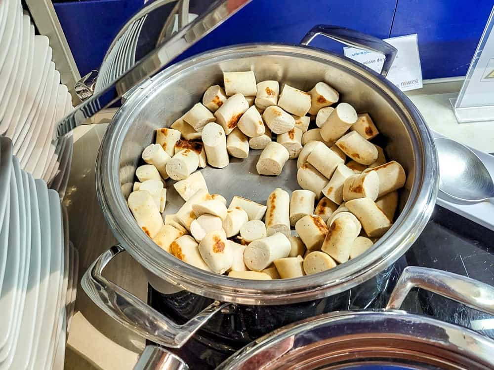 Saucisses blanches coupées en tronçons dans un plat chaud en inox du buffet