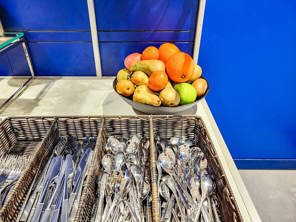 Coupe de fruits frais et paniers en osier remplis de couverts, mur bleu Air France