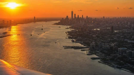 Vue aérienne de la skyline de Manhattan et de l'Hudson au coucher du soleil, depuis le hublot d'un avion de ligne