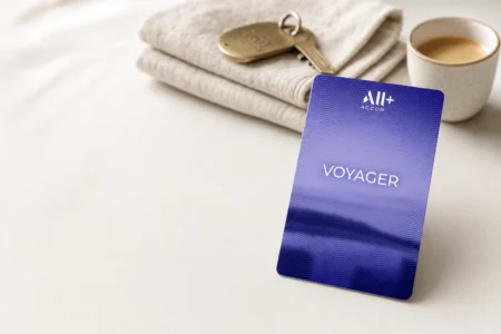 Carte d’abonnement ALL Accor+ Voyager bleue posée sur une table claire, avec du linge plié, des clés et un café